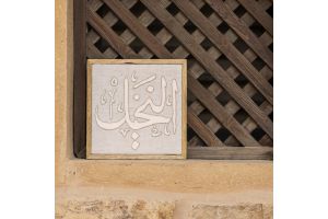 مُعلقة حائط مُطرزة بكلمة "النخيل" بالخط العربي